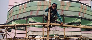 A kid is interacting with the bamboo pavilion designed and executed by Paraa