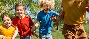 Vier Kinder mit bunten T-shirts laufen auf die Kamera zu