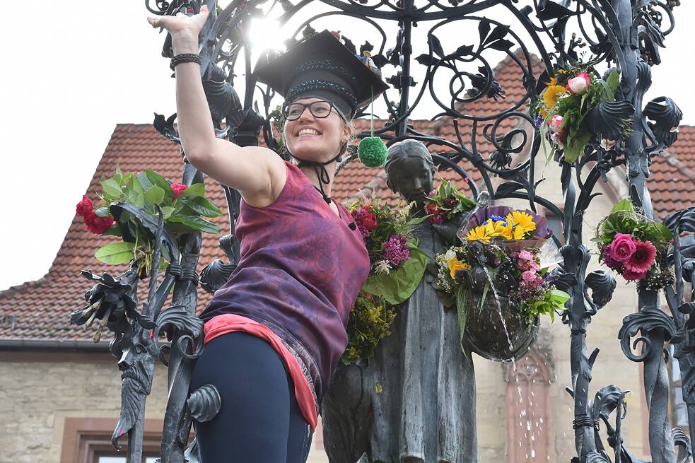 Eine frisch gebackene Doktorin klettert auf den Gänseliesel-Brunnen, um ihm Blumen zu überreichen. 