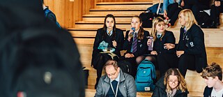 university students sitting on the stairs of a lecture theatre