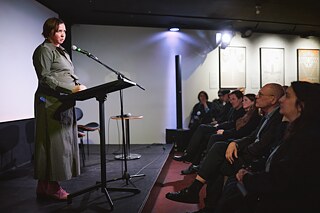 The curator of the progamme, Vera Dziadok, at the opening on stage with microphone