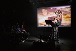 Man in the theater in front of a projection with a tiger