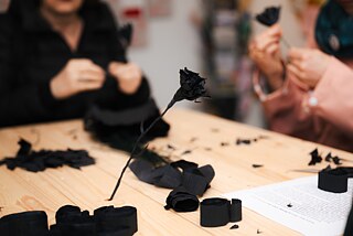Hands shape paper and wire into flowers