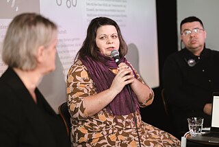 Three people sit on the stage and present the “33 Bücher für ein anderes Belarus” campaign