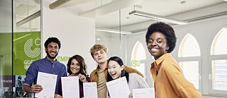 Les participants à l'examen ont réussi leur examen. Ils sont heureux et montrent fièrement leurs certificats Goethe.