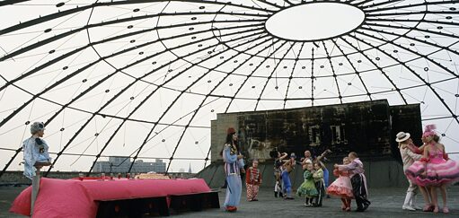 offener Dachraum mit Glasverkleidung und einer karnevalesken feiernden Truppe 
