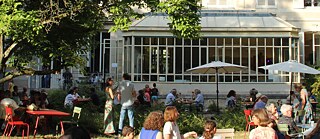 Das Foto zeigt Personen in einem sommerlichen Garten. Im Hintergrund ist das Goethe-Institut unter großen Bäumen zu sehen.