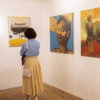 Eine Frau betrachtet Bilder einer Kunstausstellung