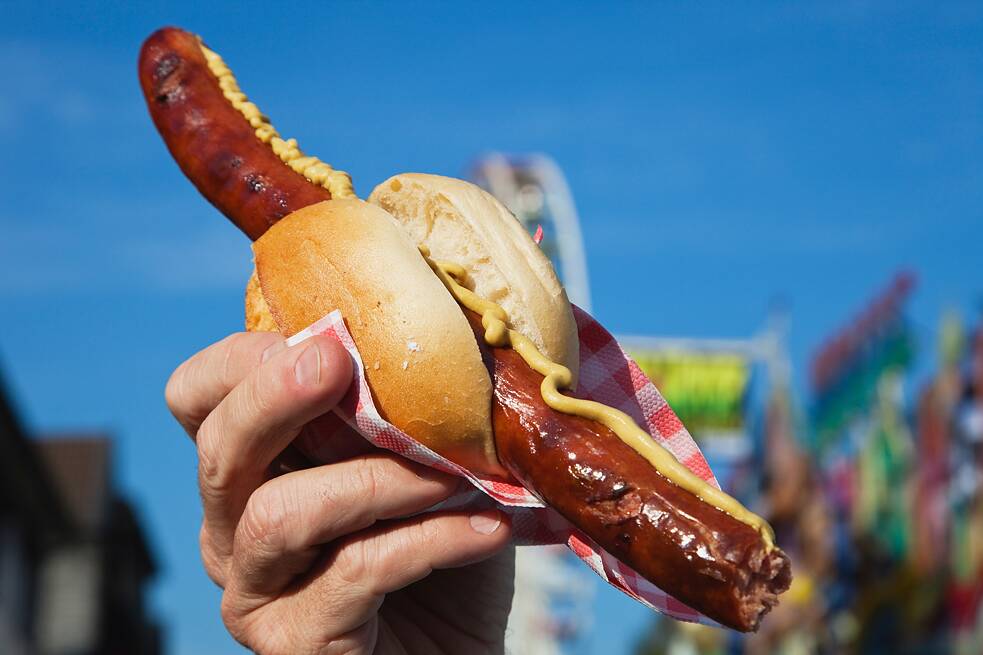 One hand holds a bratwurst in bread