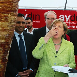 Ex-Bundeskanzlerin Angela Merkel probiert ein Stück Dönerfleisch
