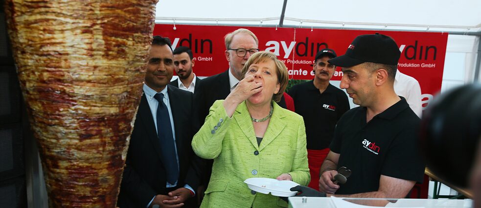 Ex-Bundeskanzlerin Angela Merkel probiert ein Stück Dönerfleisch