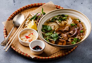 Pho Bo: Vietnamese Soup with beef in tray on concrete background