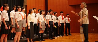 同じユニフォームを着た16人のPASCH生の合唱団が、合唱指揮者の木下マティアス義久の指揮で歌う。