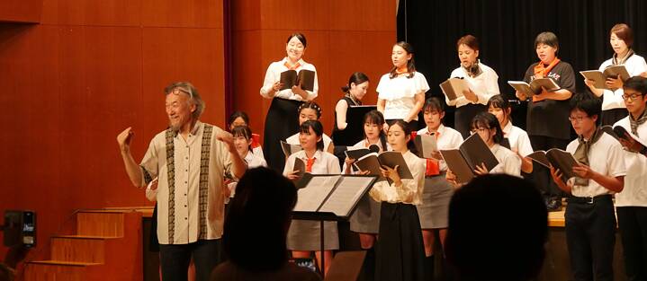 Ein Chor aus PASCH Schüler*innen und Chorleiter Yoshihisa Matthias Kinoshita treten auf vor einem Publikum