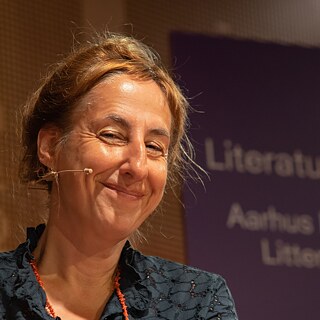 Billedet viser forfatteren Judith Hermann på en scene, mens hun smiler. © ©  Eliott Becheau / LiteratureXchange Judith Hermann