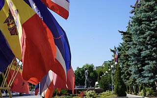 Gagauzské a moldavské vlajky pred budovou parlamentu a vlády v Comrate, v pozadí socha Lenina.
