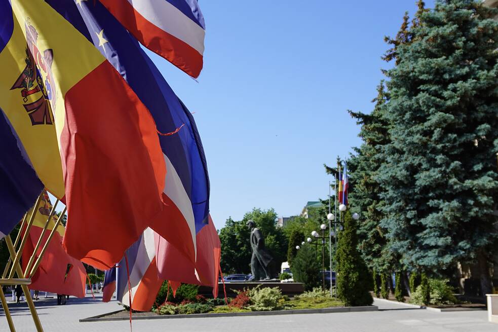 Moldauische und gagausische Flagge vor dem Parlaments- bzw. Regierungsgebäude in Comrat, eine Leninstatue im Hintergrund.