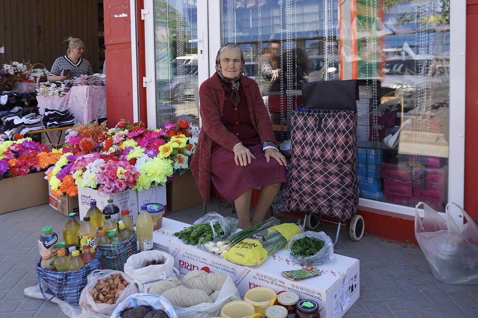 Dôchodkyňa ponúka svoj tovar na predaj na trhovisku v Comrate.