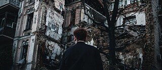 Ein man schaut auf das von einer Rakete zerstörte Gebäude 