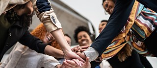 Verschiedene Menschen halten sich an den Händen.