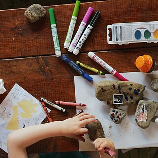 Image of a child drawing with rocks and craft materials
