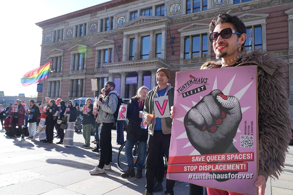 Allessandro (r) holds a poster with the inscription “Tuntenhaus bleibt –Save queer Spaces” in front of the Berlin House of Representatives