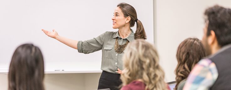 Eine Dozentin spricht vor einem Whiteboard zu Ihren Studenten. Eine Studentin hat ein Laptop vor sich. Bildauswahl der Region SOE zur Kultur- und Spracharbeit.