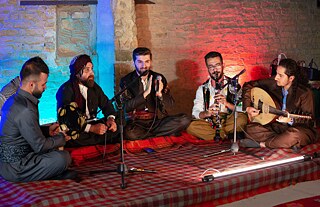 Fünf männliche Musiker spielen Instrumente und singen zusammen