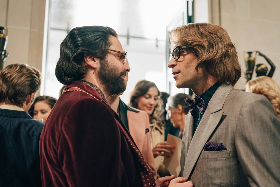 In einer Szene aus der Serie "Becoming Karl Lagerfeld" blicken sich Yves Saint-Laurent und Karl Lagerfeld einander an, beide seitlich zu sehen.