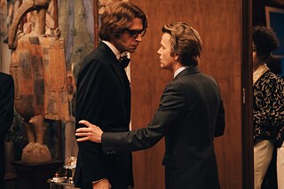 In a scene from the series 'Becoming Karl Lagerfeld', Pierre Bergé stands in front of Yves Saint-Laurent and grabs him by the arm