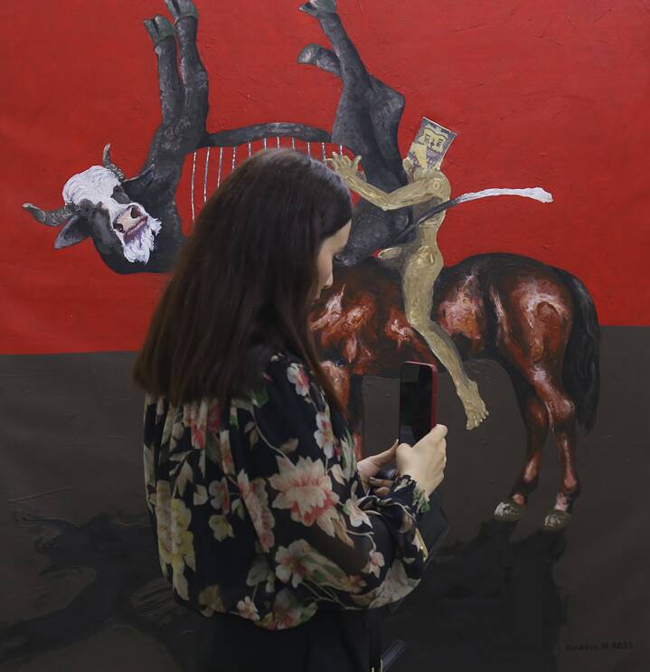 Frau steht mit Mobiltelefon vor einem Kunstwerk