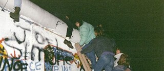 Junge Frauen klettern mitten in der Nacht auf die Berliner Mauer.