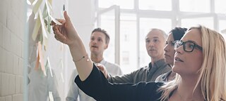 Gruppe mit Notizblättern an Tafel