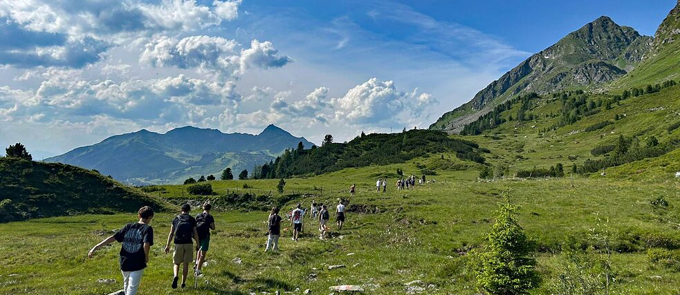 Jugendliche wantern in den Alpen.