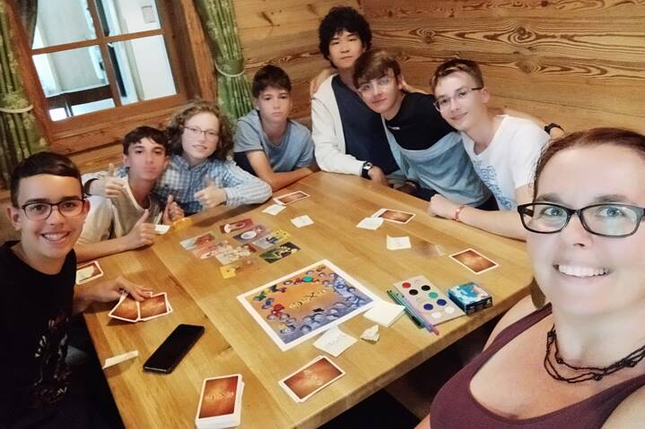 Jugendliche posieren für ein Selfie, auf einem Tisch liegen Spielkarten.