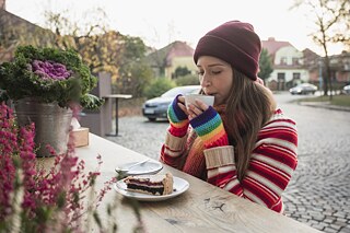 Junge Frau trinkt Kaffee und isst Kuchen