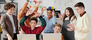 Die Lehrerin schaut, wie die Kinder am Computer arbeiten