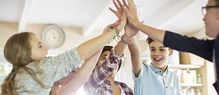 Schüler*innen klatschen im Klassenzimmer die Hände gegeneinander.