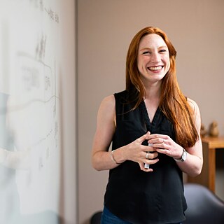 Friendly teacher stands in front of whiteboard