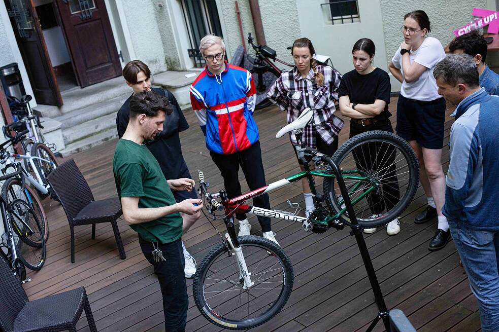 People standing around a bicycle that is been fixed by kola