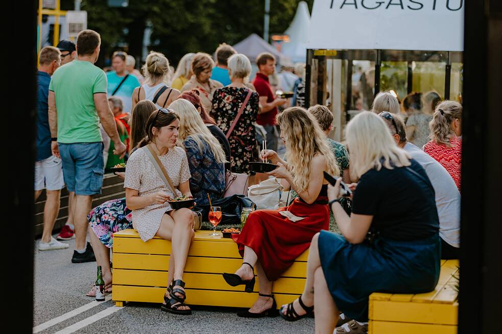 People sit and talk on the car free avenue.