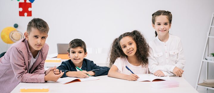 Vier Kinder sitzen an einem Tisch. 