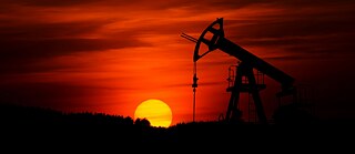 Photo is showing a Pump-jack mining crude oil in the sunset. 