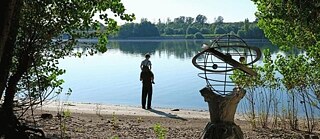 Ein Mann mit Kind auf den Schultern blickt aufs Wasser