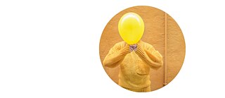 Das runde Bild zeigt eine Person in einem gelben Pullover, die einen gelben Luftballon vor dem Gesicht hält.