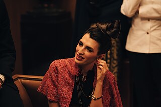 The Spanish-French designer Paloma Picasso in a scene from the series "Becoming Karl Lagerfeld", touching her golden earring with her fingers.