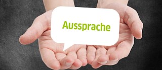 In den Händen sieht man grünen Text "Aussprache"