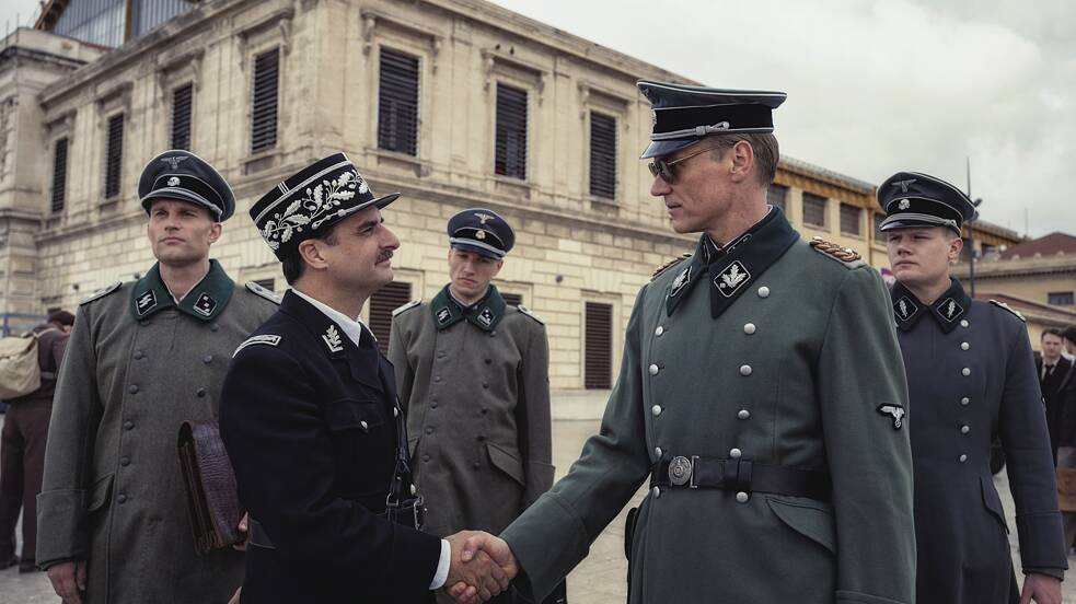 Schrader (Markus Gertken),  líder de grupo da SS, encontra oficiais de Vichy. Still da série “Transatlântico” da Netflix.