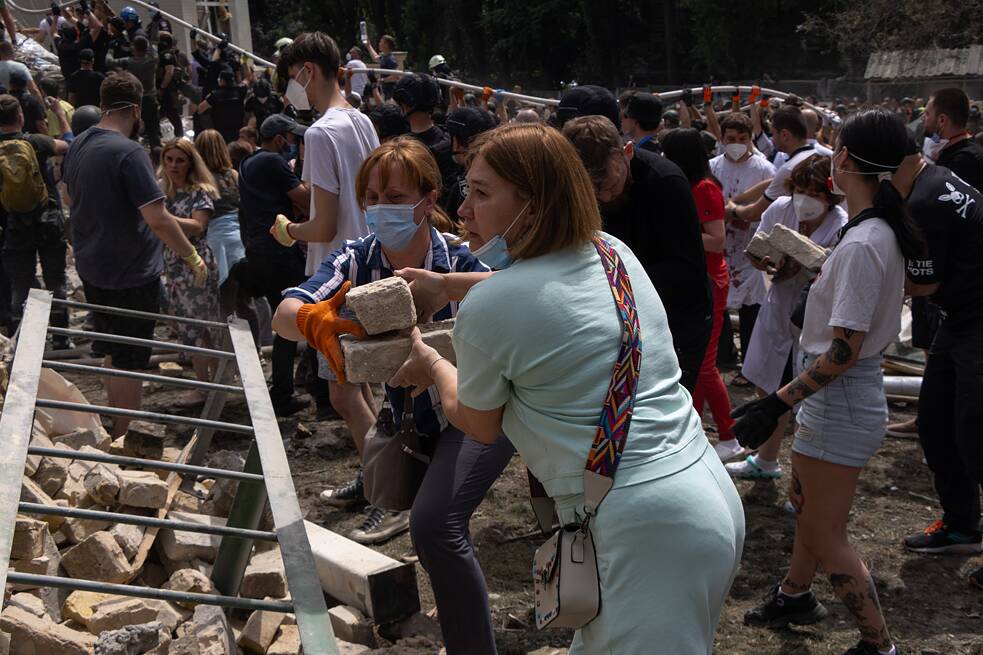 Ženy odklízejí trosky po ostřelování nemocnice Ochmatdyt v Kyjivu