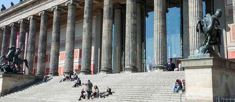 Gent asseguda en les escales enfront d'un museu